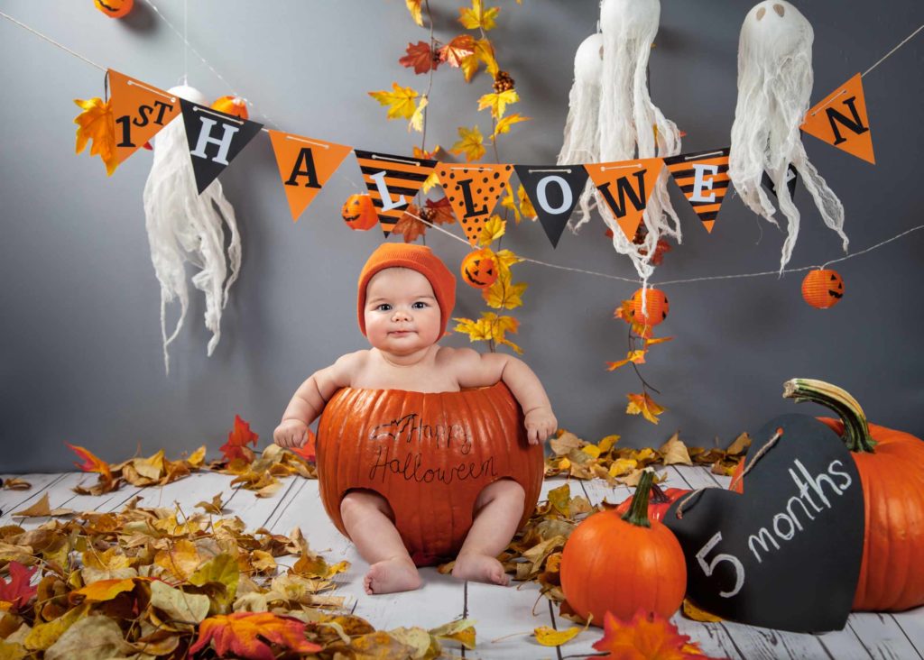 5-month-old baby in a carved pumpkin with halloween decors