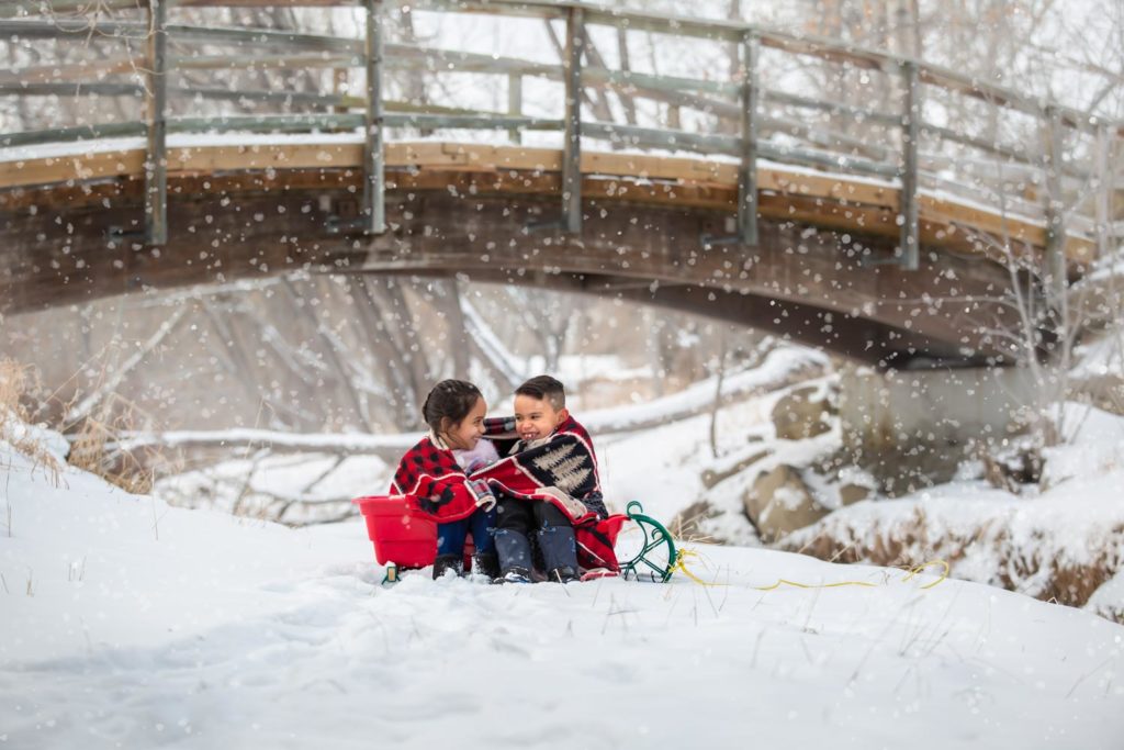 two kids in a sled under a bridge