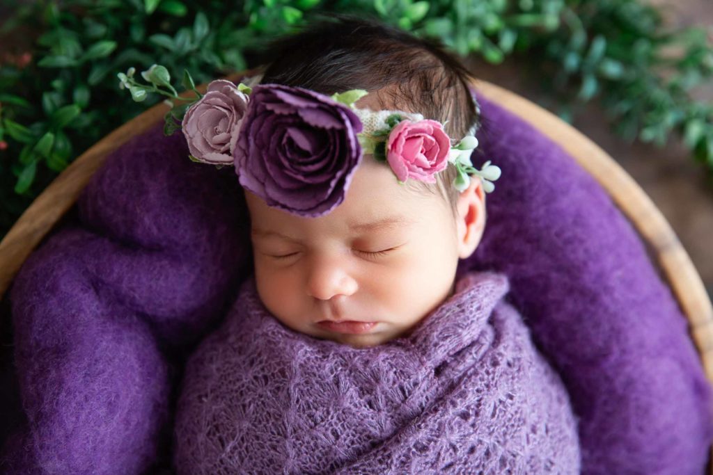 newborn baby with purple blankets