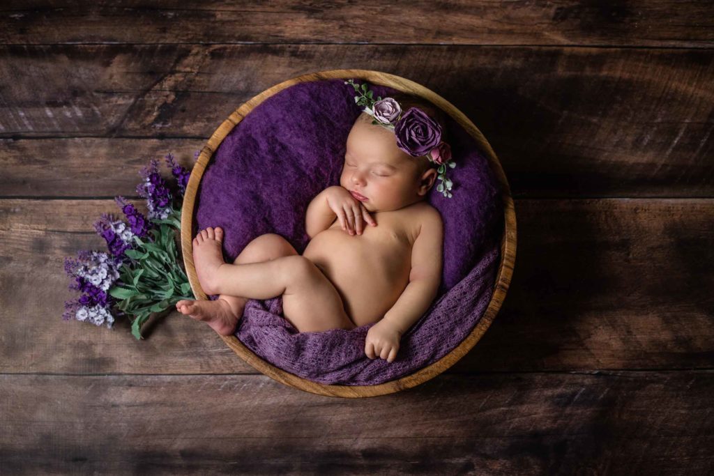 newborn baby with purple flowers