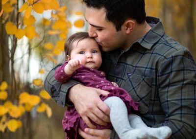 father holding baby among trees