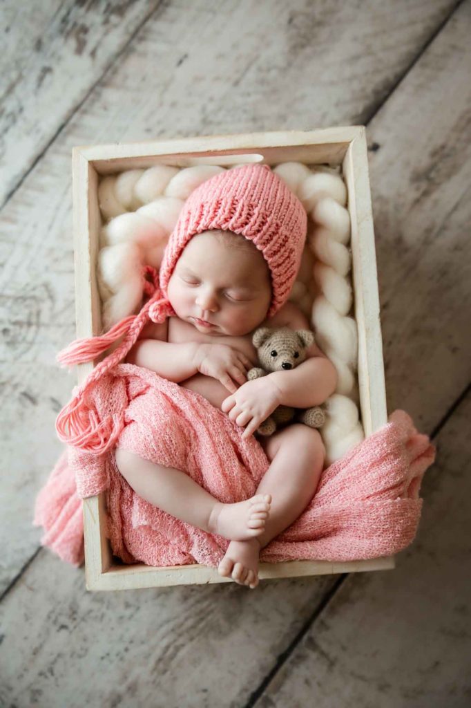 newborn baby hugging teddy bear