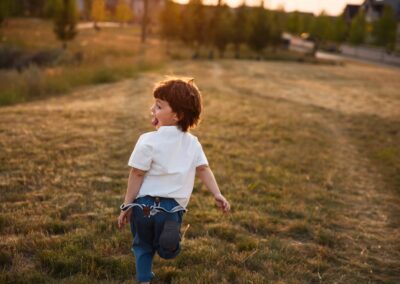 Toddler boy running through a golden field in fall light