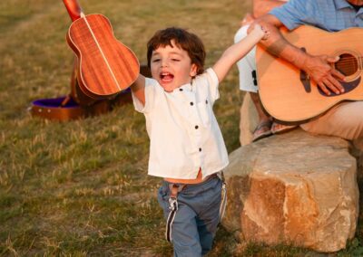 3 year old boy holding a ukulele up in the air