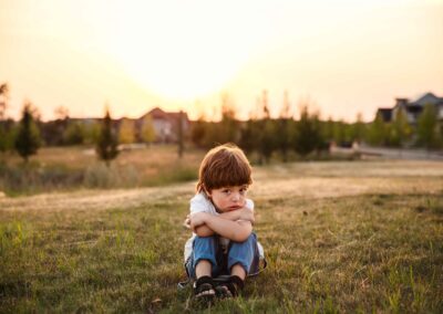 little boy sitting and pouting on the grass