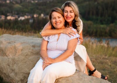 Mother embracing her mother while sitting on a large rock