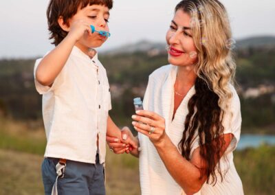 Mother blowing bubbles with her son on a hilltop